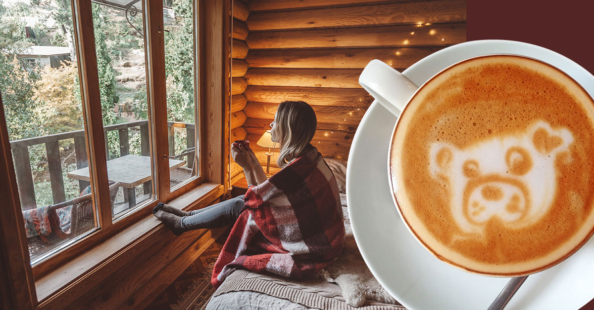 A woman with a big cup of coffee is looking out the window.